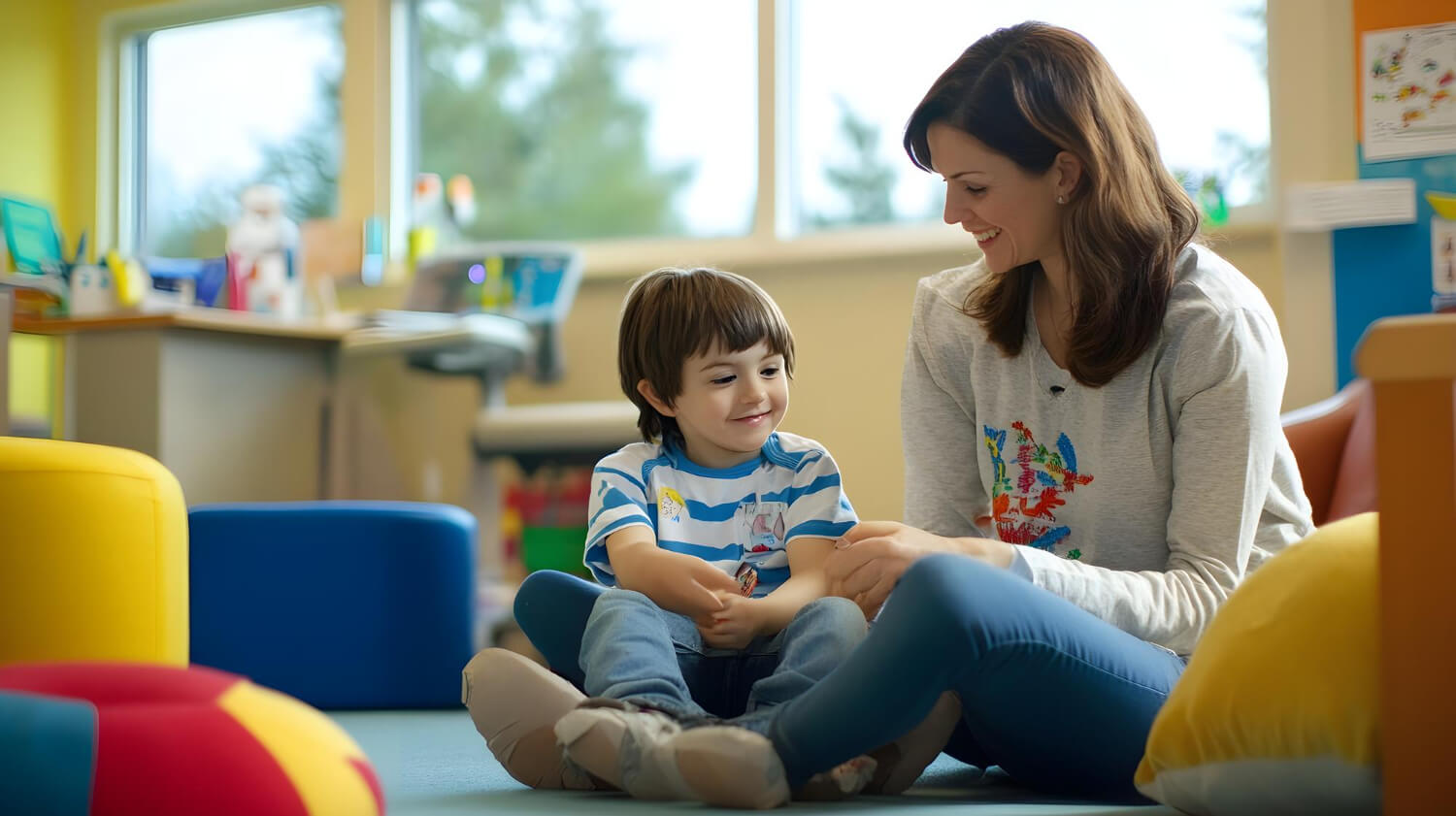 BCBA sitting on the floor, smiling and interacting with a child during ABA therapy session.