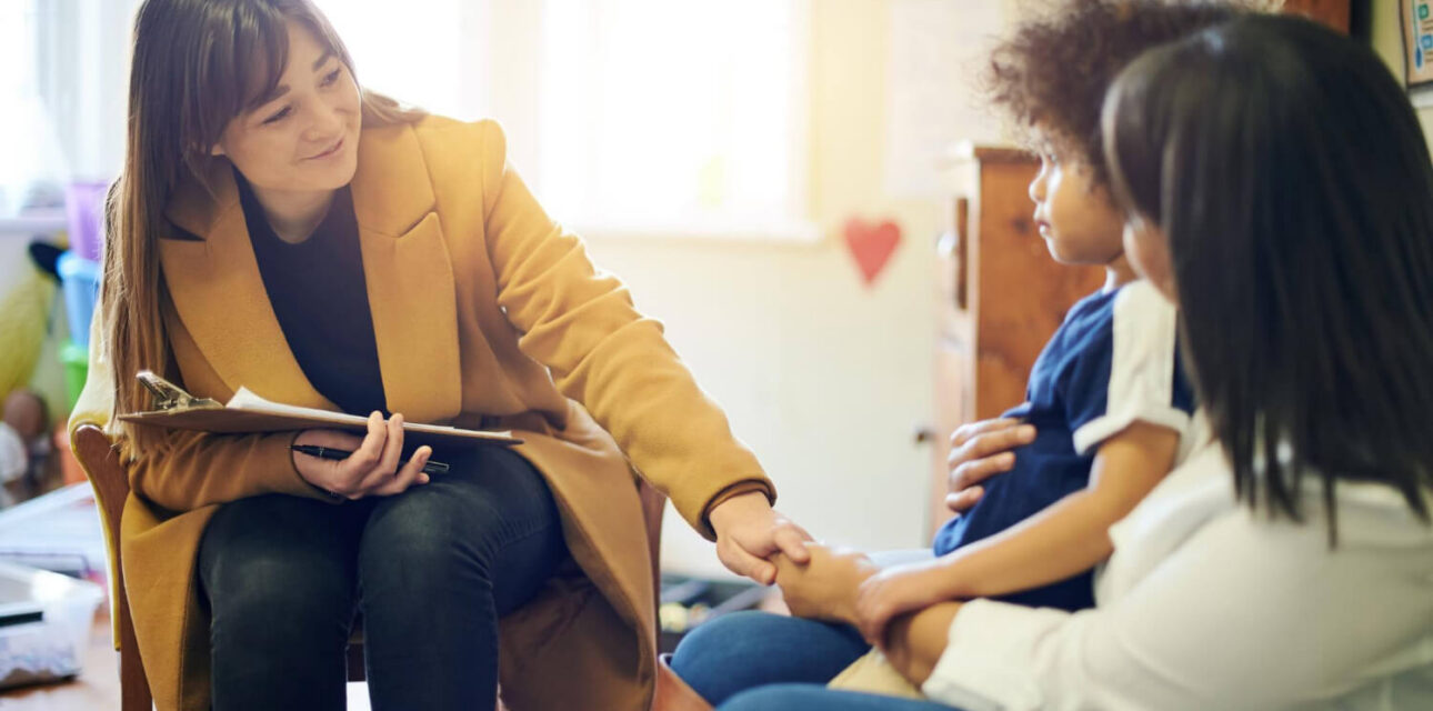 ABA therapist speaking with a parent and young child during an ABA therapy session.