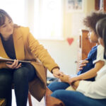 ABA therapist speaking with a parent and young child during an ABA therapy session.