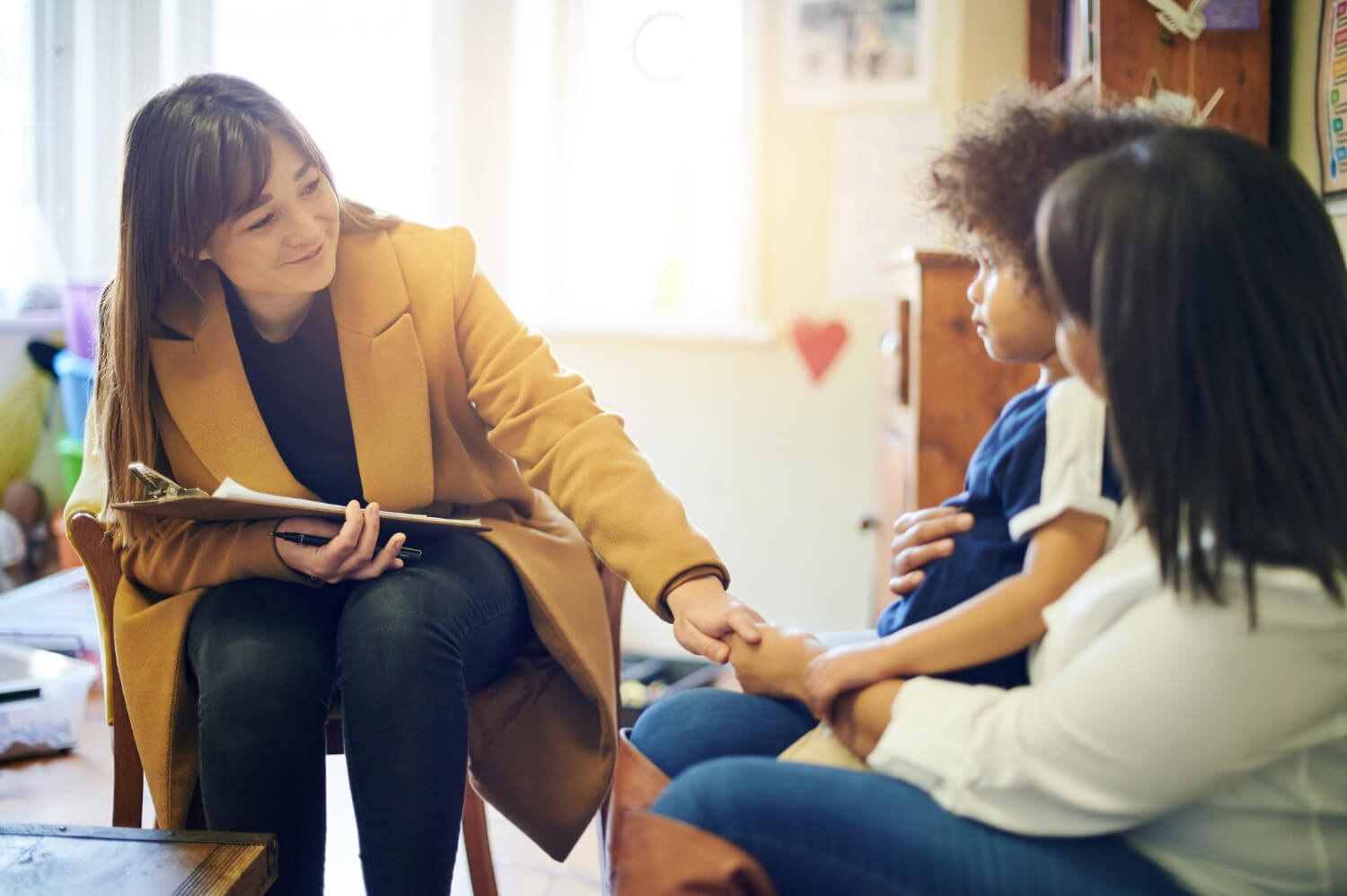 ABA therapist speaking with a parent and young child during an ABA therapy session.