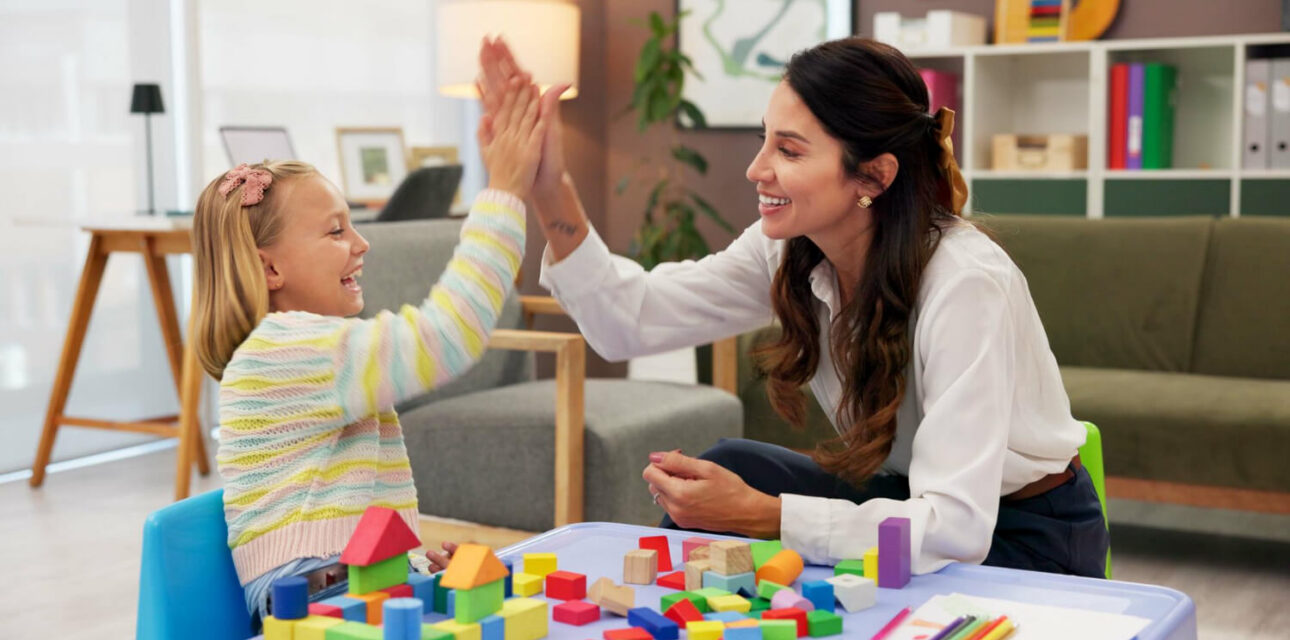 BCBA and child giving a high-five during a colorful block-building activity.