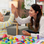 BCBA and child giving a high-five during a colorful block-building activity.