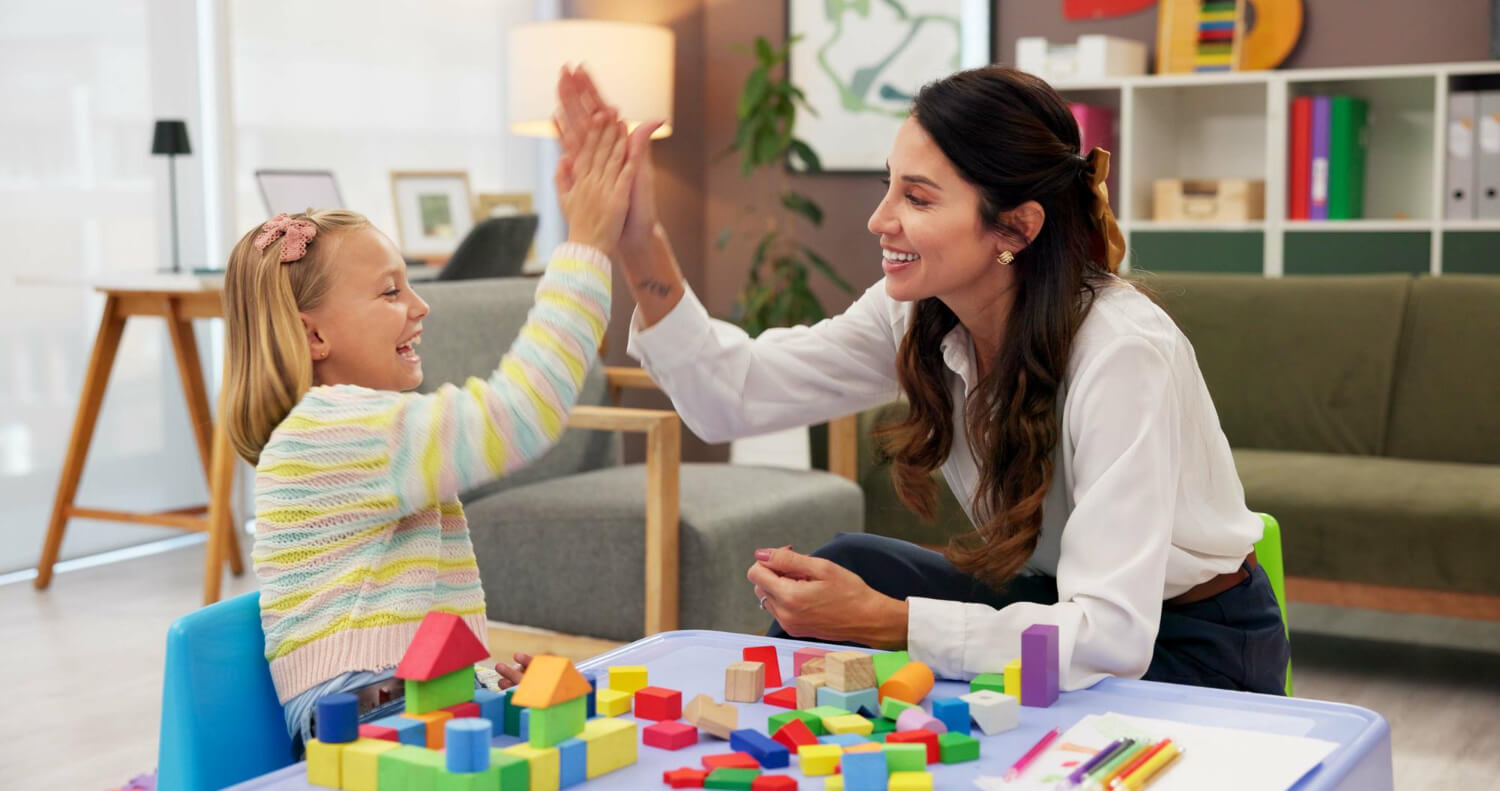 BCBA and child giving a high-five during a colorful block-building activity.