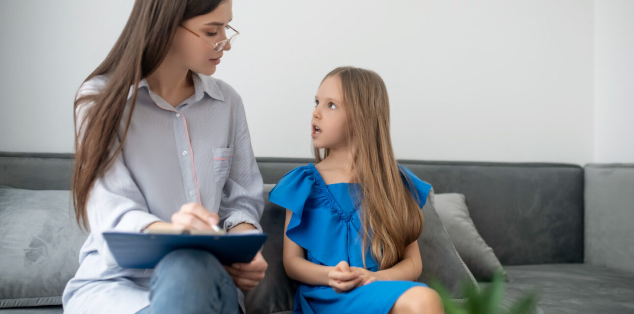 BCBA speaking with a child on a couch during ABA therapy.