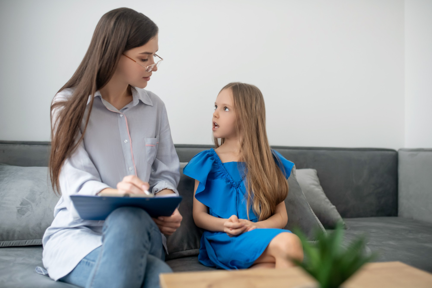 BCBA speaking with a child on a couch during ABA therapy.