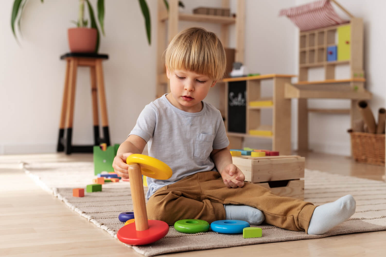 Toddler playing with a stacking ring toy on the floor during ABA therapy.