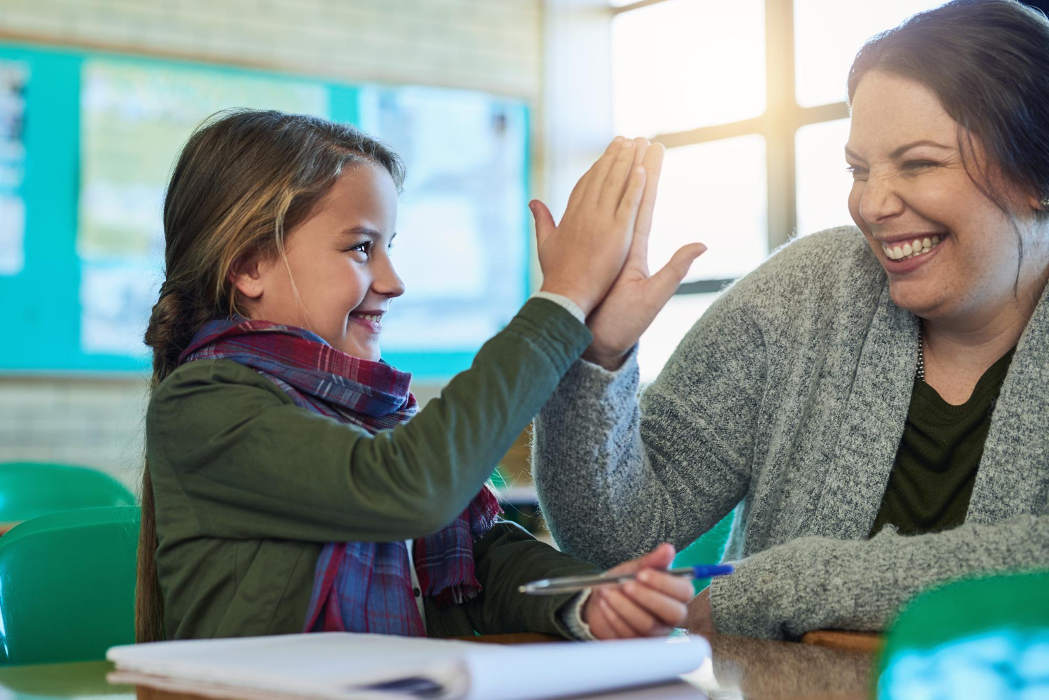 A smiling child and BCBA high-five in an ABA therapy center.