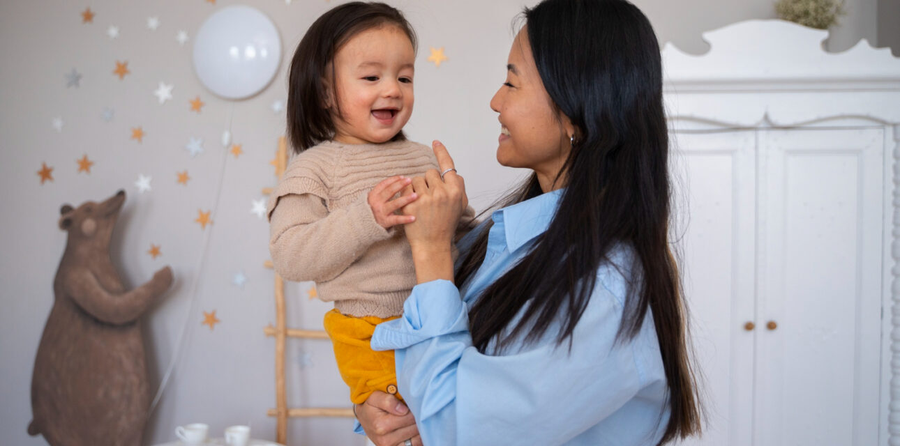 Mother holding her smiling toddler with autism in an ABA therapy center.