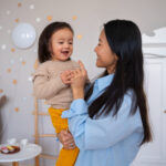 Mother holding her smiling toddler with autism in an ABA therapy center.