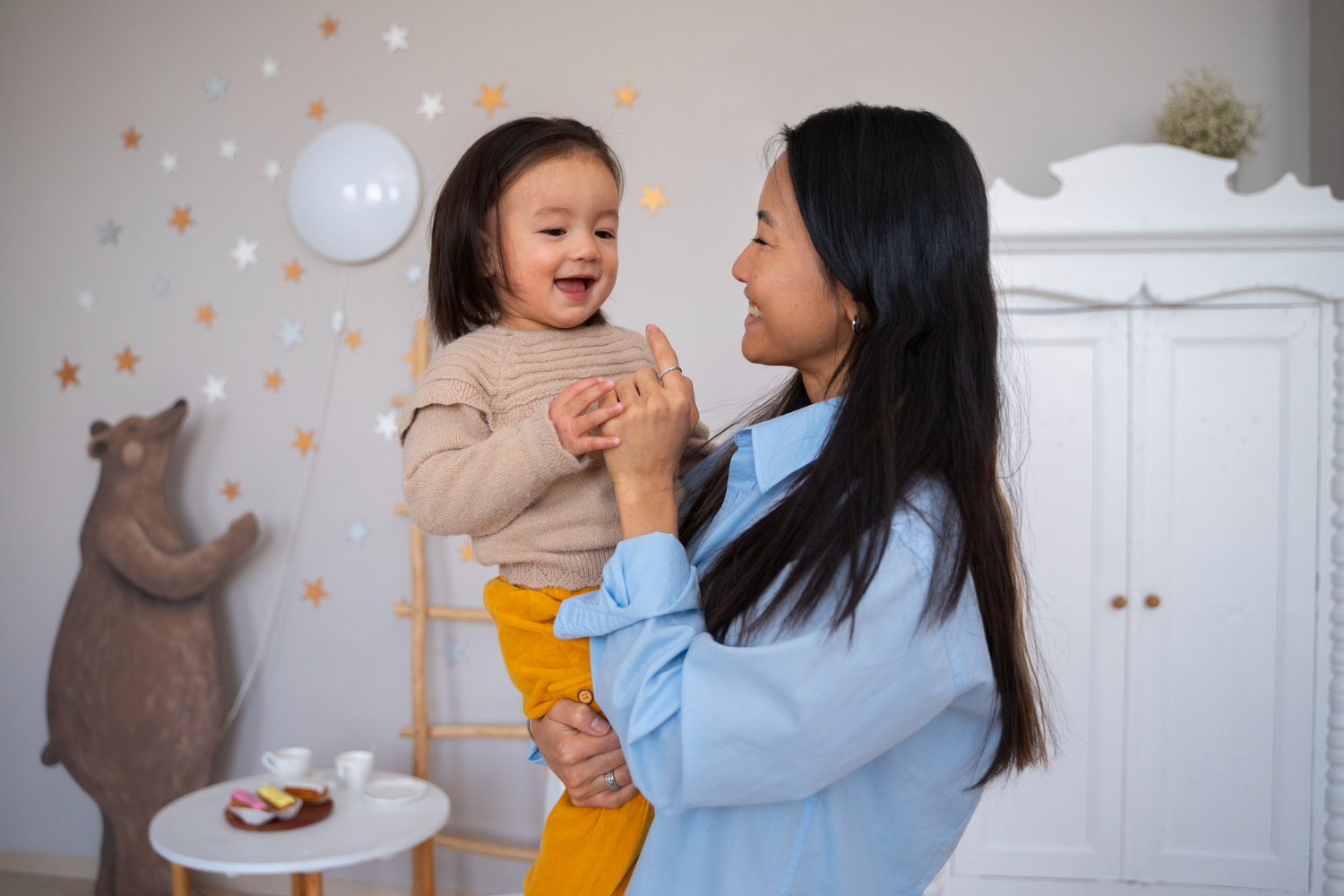 Mother holding her smiling toddler with autism in an ABA therapy center.