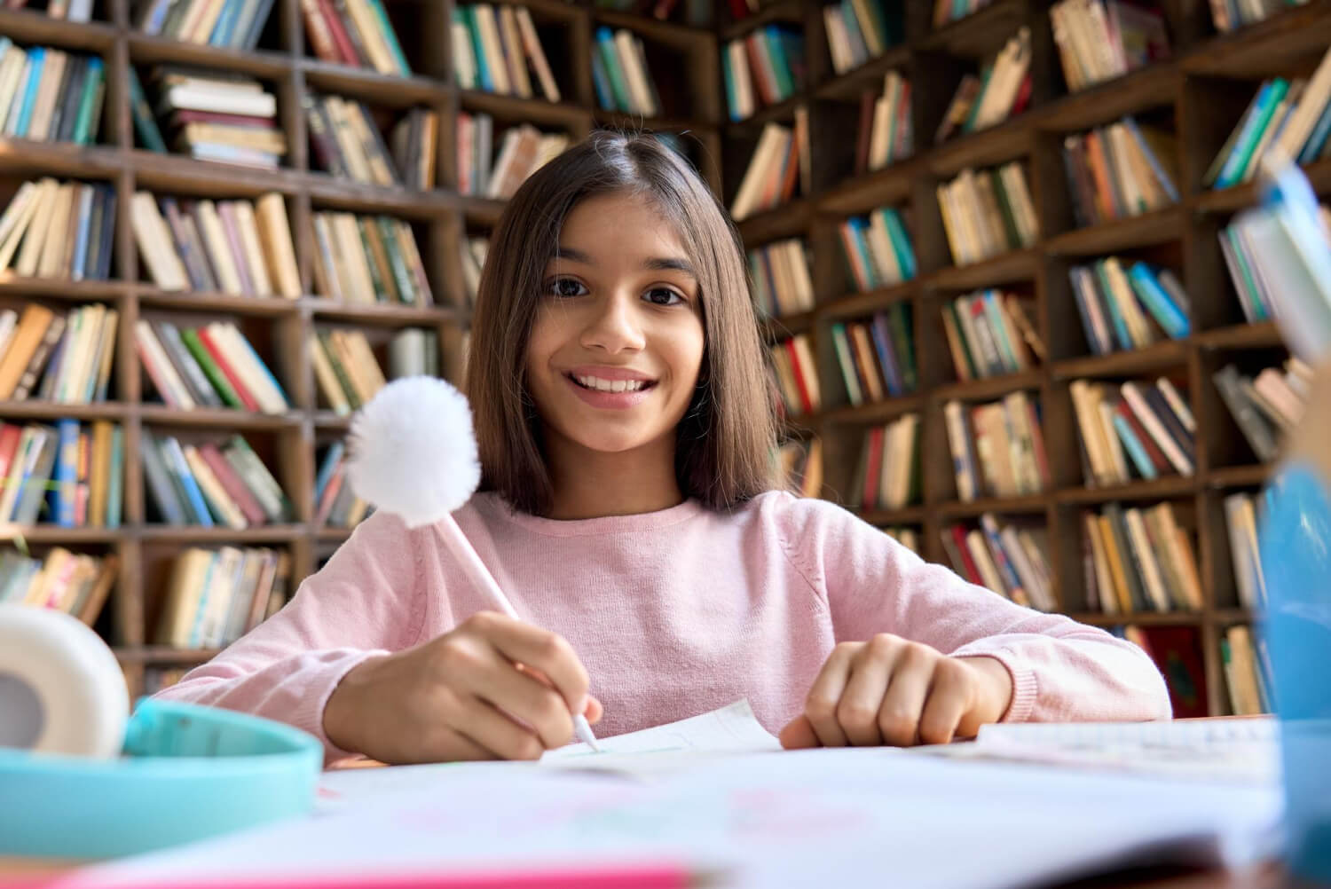 Autistic child smiling while writing at a desk in a library.
