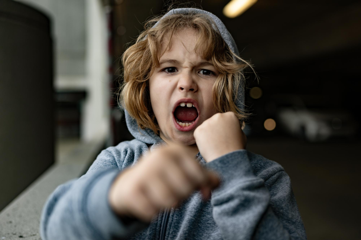 Autistic child showing frustration with clenched fists and open mouth.