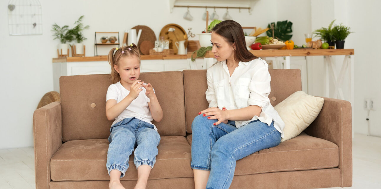 Adult sitting with a child during an in-home ABA therapy session on a living room couch.