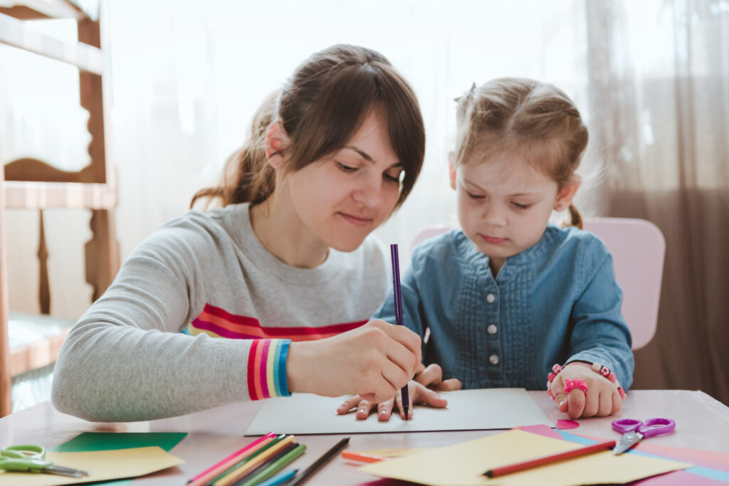 BCBA helping a child with arts and crafts at a table.