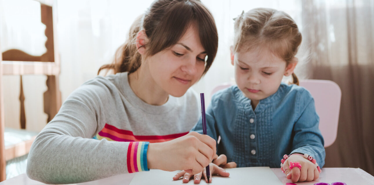 BCBA helping a child with arts and crafts at a table.