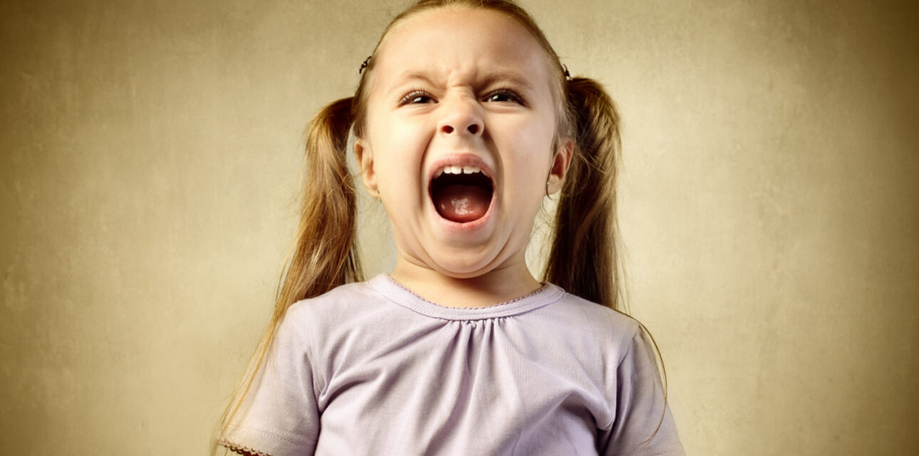 Young child with autism screaming with an upset facial expression.