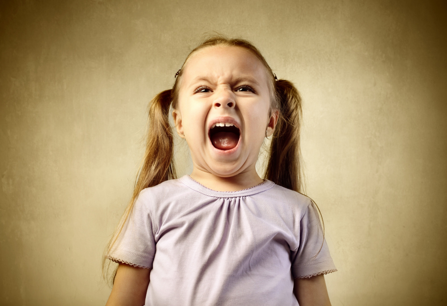 Young child with autism screaming with an upset facial expression.