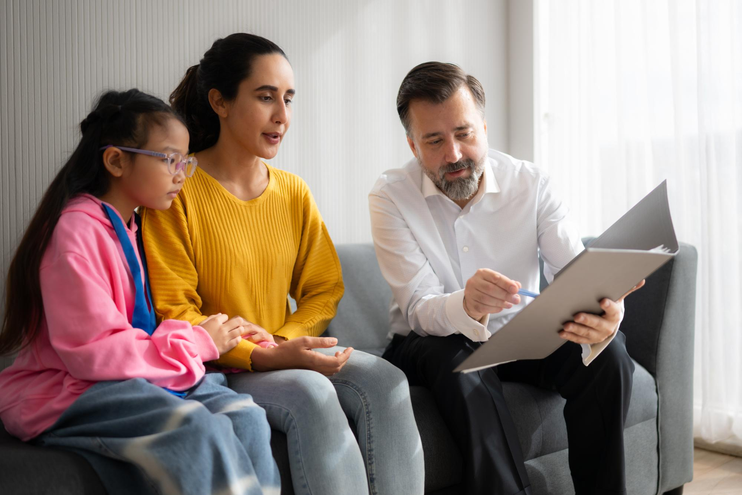 A BCBA reviews documents with a parent and child during an ABA therapy consultation.