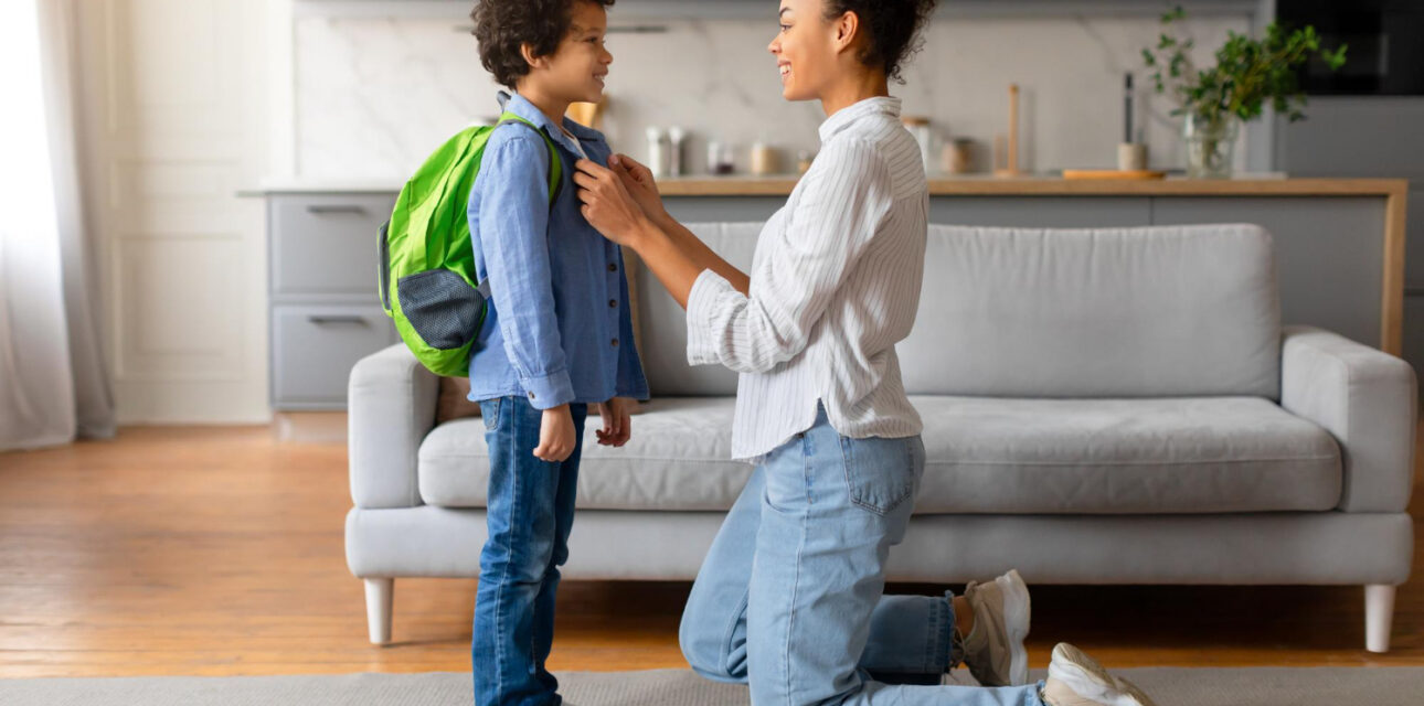 BCBA helps an autistic child get ready for school by adjusting his backpack.