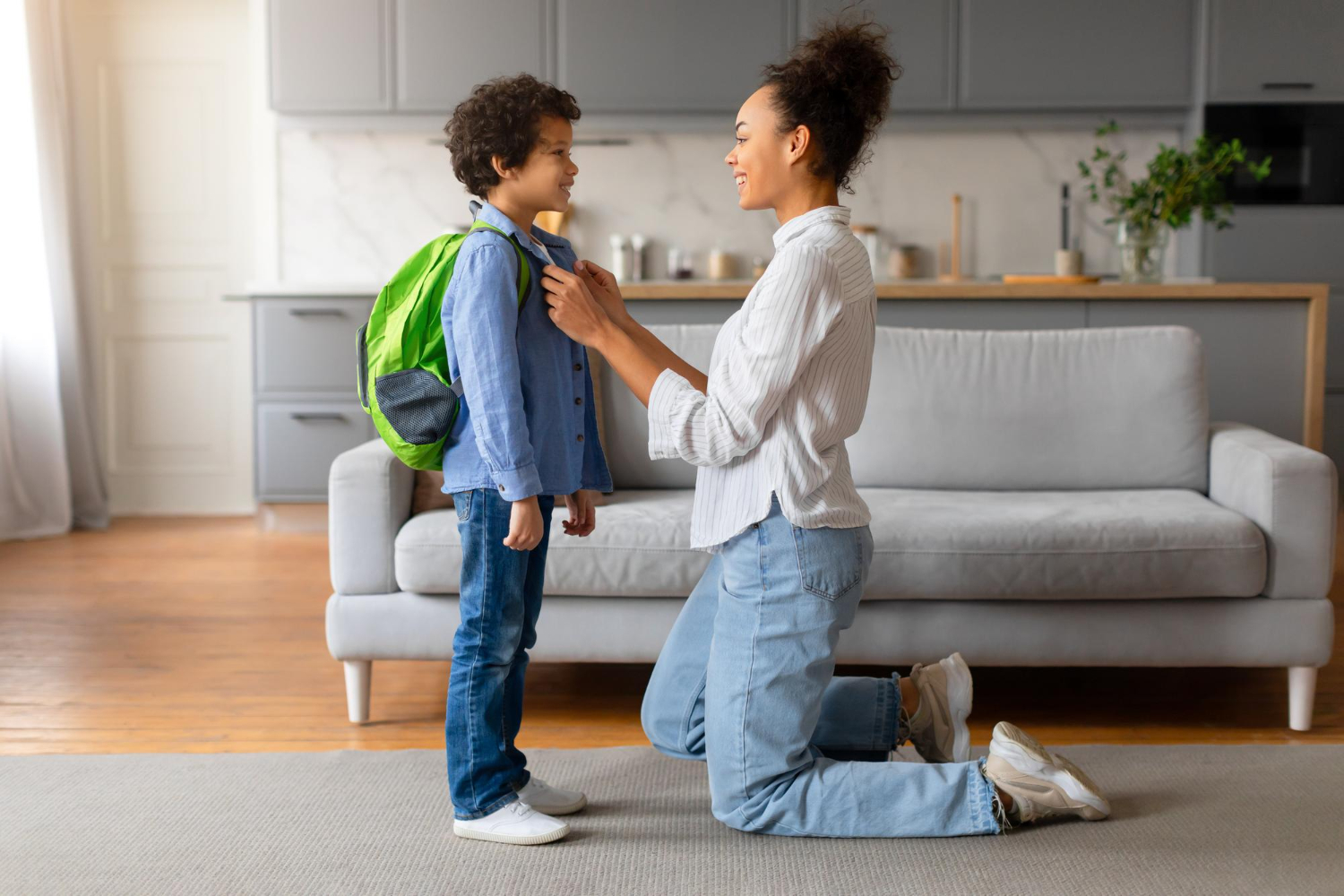 BCBA helps an autistic child get ready for school by adjusting his backpack.