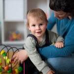 BCBA supports an autistic child playing with a bead maze toy.