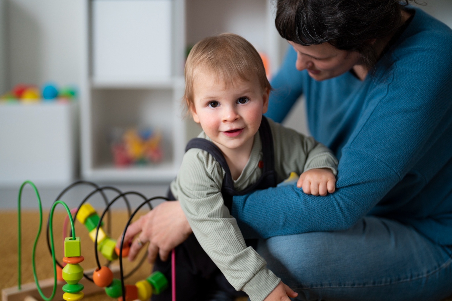 BCBA supports an autistic child playing with a bead maze toy.