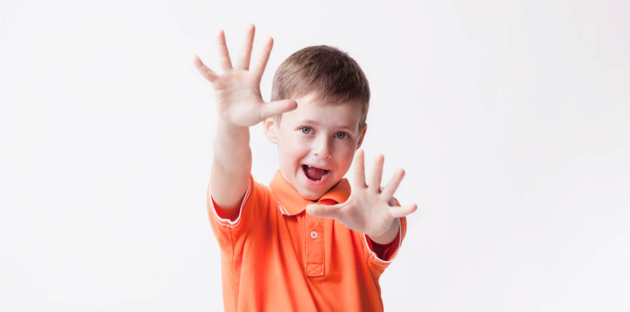 Young autistic child stimming with raised hands.