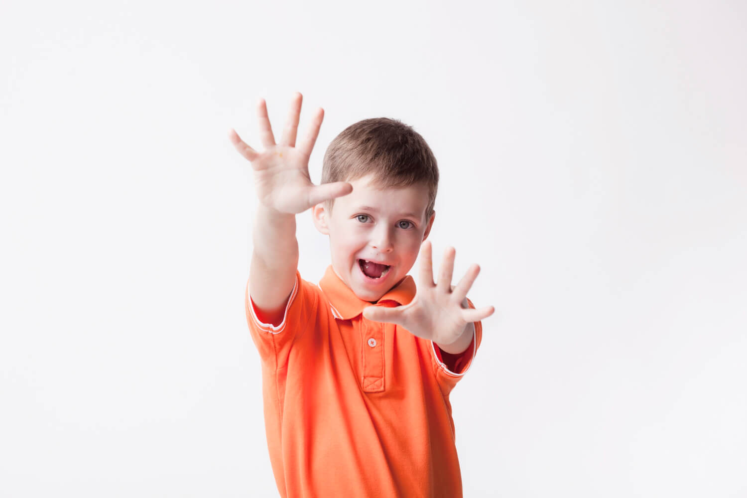 Young autistic child stimming with raised hands.