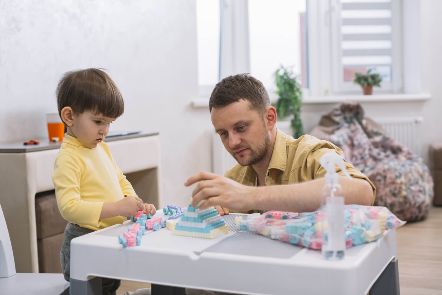 ABA therapist helping a young child build with blocks during a play-based therapy session.