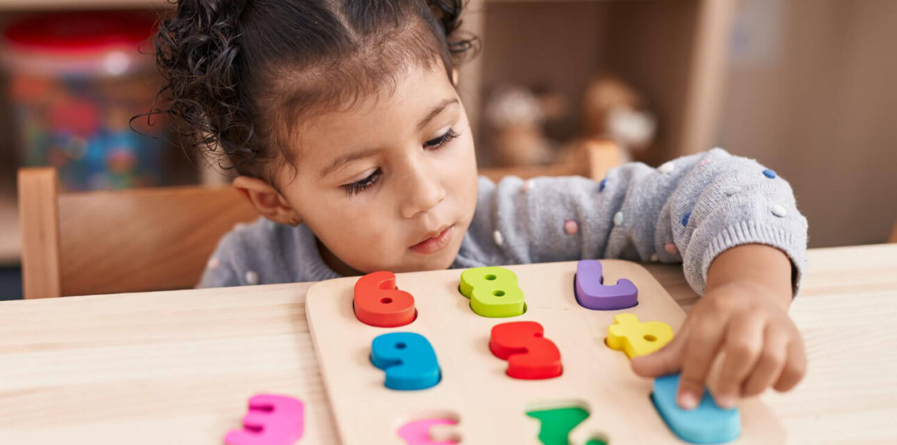 Preschool child completing a colorful number puzzle during ABA therapy.