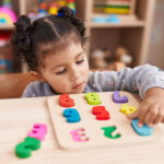 Preschool child completing a colorful number puzzle during ABA therapy.