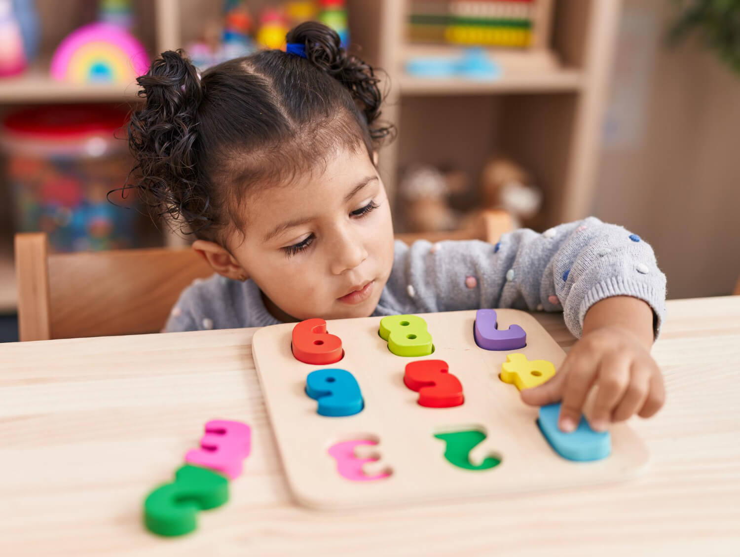 Preschool child completing a colorful number puzzle during ABA therapy.