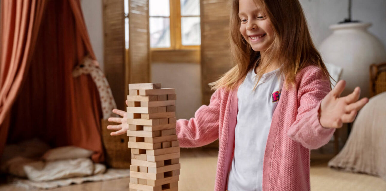 Girl with autism playing with wooden blocks during an ABA therapy activity at home.