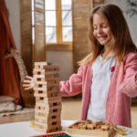 Girl with autism playing with wooden blocks during an ABA therapy activity at home.