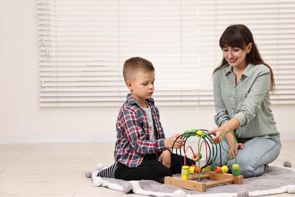 Child with autism working on a bead maze with a therapist during an ABA therapy session.