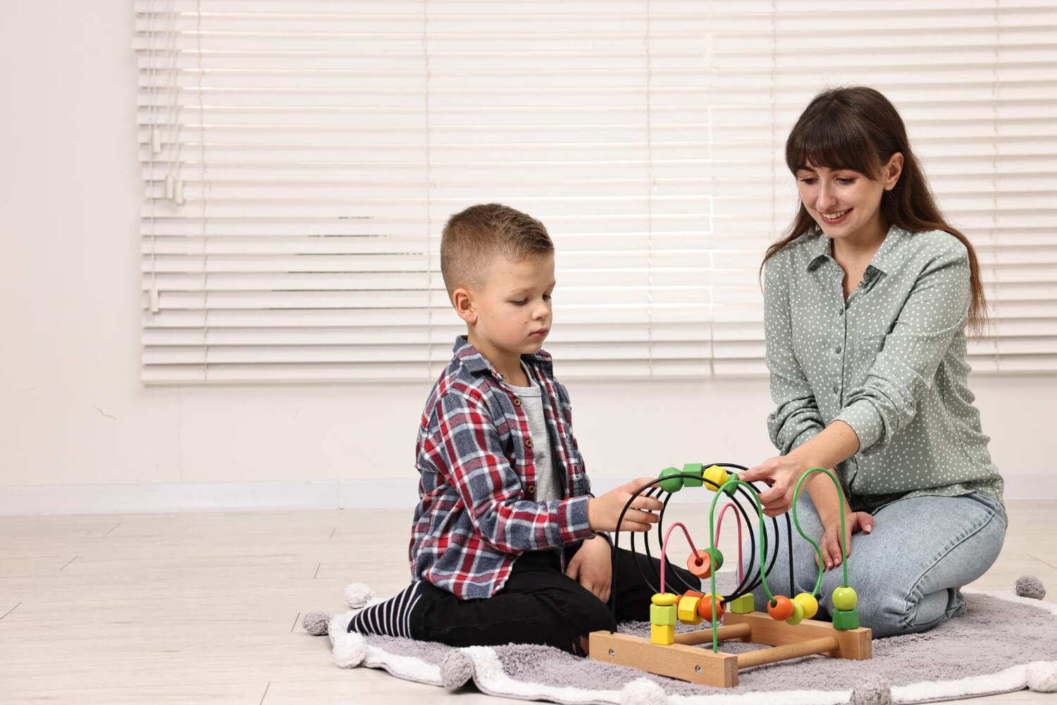 Child with autism working on a bead maze with a therapist during an ABA therapy session.