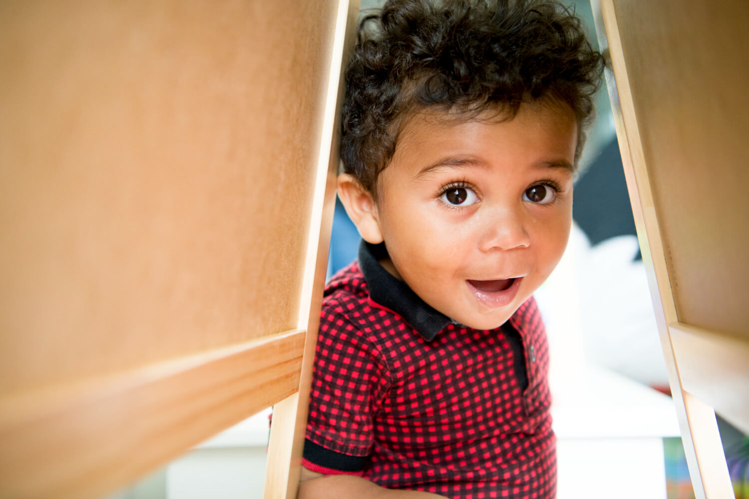 Young child peeking through a play structure during an autism-related activity.