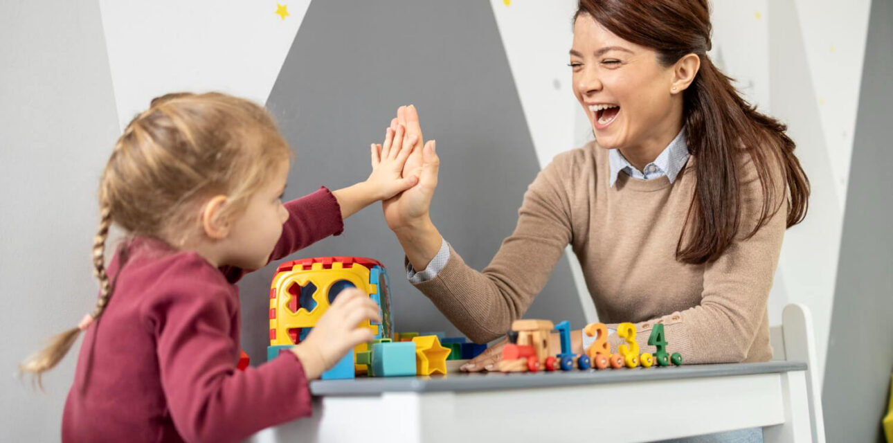 Child high-fiving an ABA therapist during a pairing session.