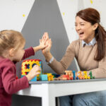 Child high-fiving an ABA therapist during a pairing session.