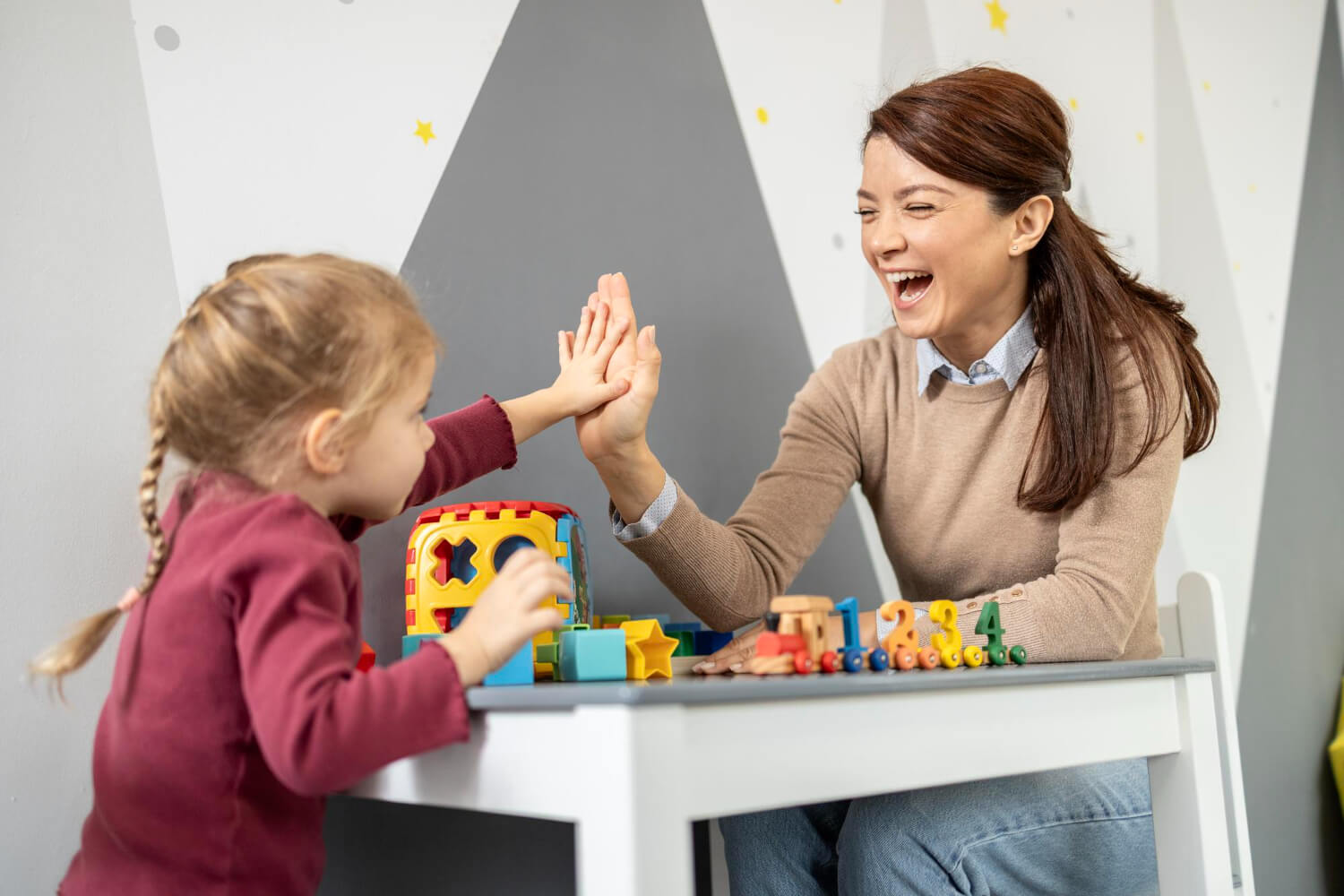 Child high-fiving an ABA therapist during a pairing session.