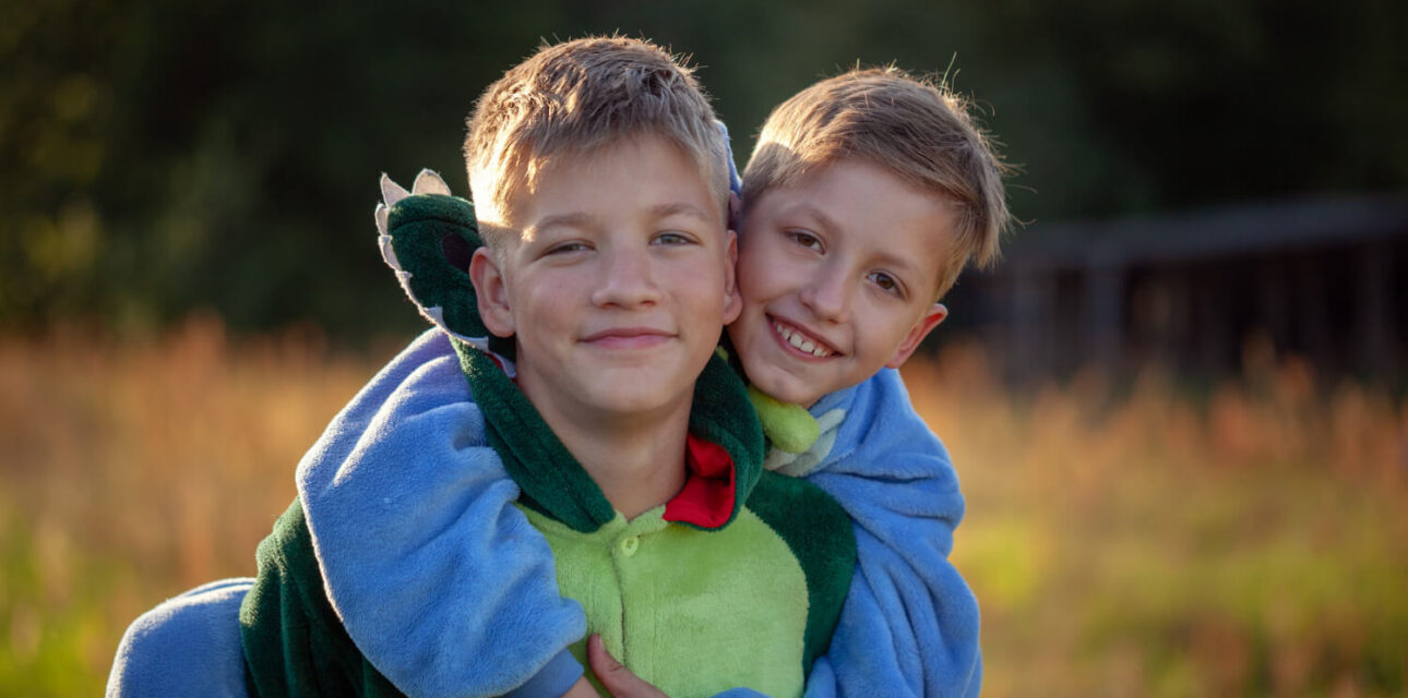 Brothers smiling and hugging outdoors.