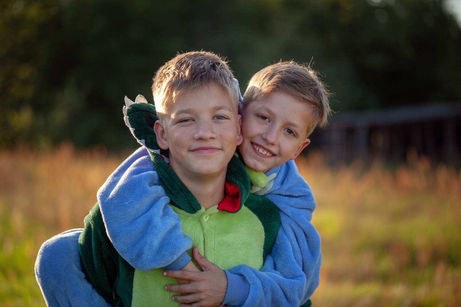 Brothers smiling and hugging outdoors.