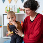 BCBA supporting a young child with autism during ABA therapy.