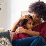 Mother comforting her autistic daughter at home with support from BCBA-led ABA therapy.