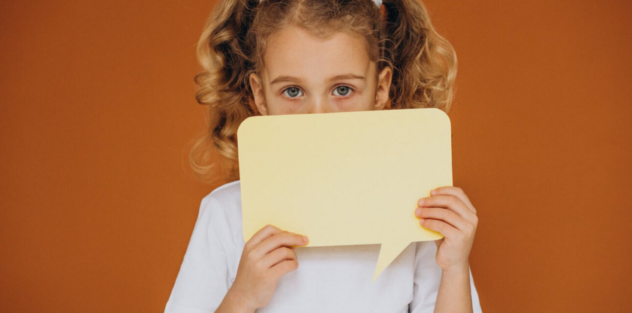 Young girl with autism holding a speech bubble card while learning to communicate.