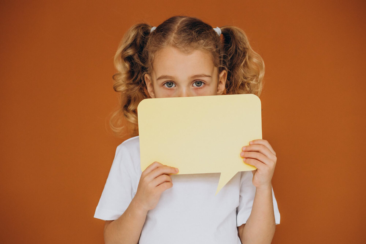 Young girl with autism holding a speech bubble card while learning to communicate.